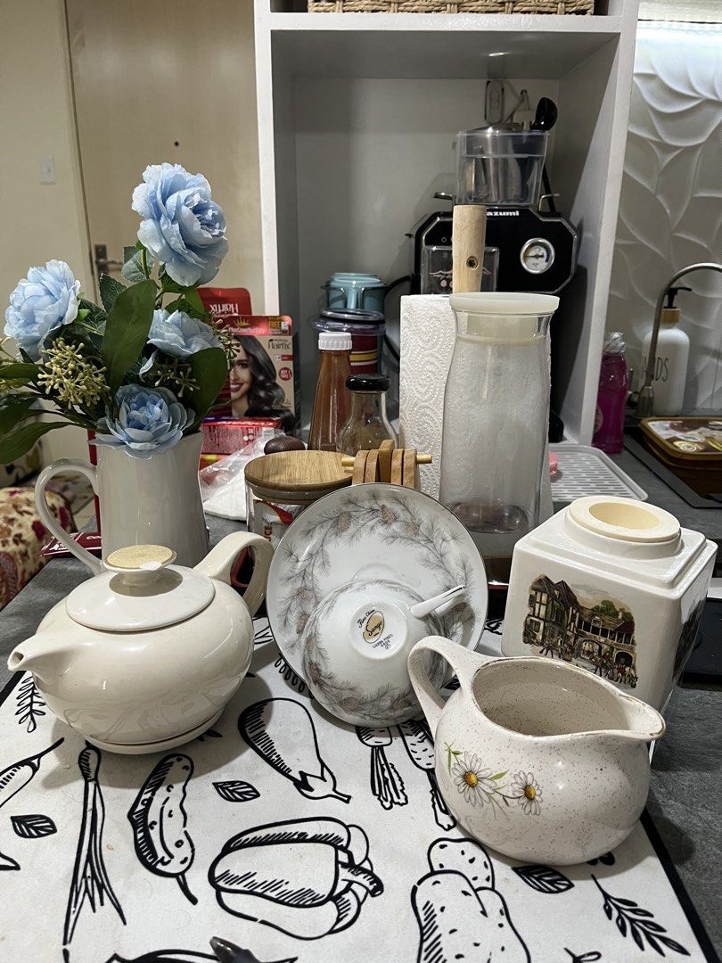Vintage Ceramic Teapot (small chip) and Tableware Collection (Category: Coffee & Tea Tableware) located in Caloocan City. Submitted by happypenguin-808164 (Listing ID 1467022956, Image 2). Description: - Bundle of ceramic kitchen and tea pieces - Includes cream teapot, matching saucer and cup - Features speckled cream pitcher with daisy decals - Includes square tea canister with charming village illustrations - Great for afternoon tea or home dec
