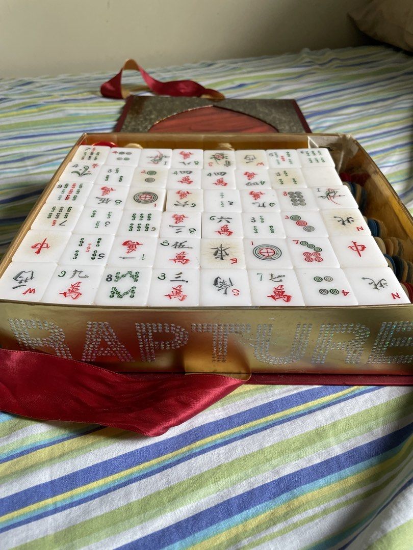 Vintage Mahjong Set with dice and Chips (Category: Board Games & Puzzles) located in Cebu City. Submitted by modelrunway (Listing ID 1466989156, Image 2). Description: - Complete mahjong set featuring traditional white tiles with classic Chinese character, circle, and bamboo carvings - Housed in a stunning decorated gold box branded with RAPTURE on the side - Includes a shiny gold interior, red ribbon handle, and multicolored gaming chips - Perfe