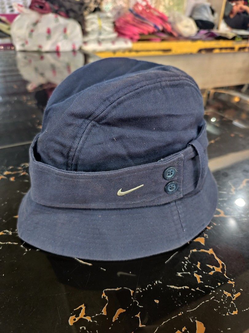 Vintage Nike Bucket Hat Size M/L (Category: Caps & Hats) located in Cordova. Submitted by bsb.streetluxvintage.clothing (Listing ID 1466974993, Image 1). Description: - Brand: Nike - Color: Navy blue - Size: M/L - Material: Cotton with satin-like quilted lining - Details: Embroidered white swoosh logo, two decorative side buttons - Condition: Clean interior - Origin: Made in China.