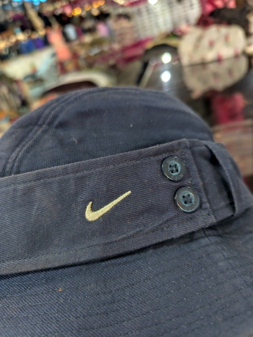 Vintage Nike Bucket Hat Size M/L (Category: Caps & Hats) located in Cordova. Submitted by bsb.streetluxvintage.clothing (Listing ID 1466974993, Image 2). Description: - Brand: Nike - Color: Navy blue - Size: M/L - Material: Cotton with satin-like quilted lining - Details: Embroidered white swoosh logo, two decorative side buttons - Condition: Clean interior - Origin: Made in China.