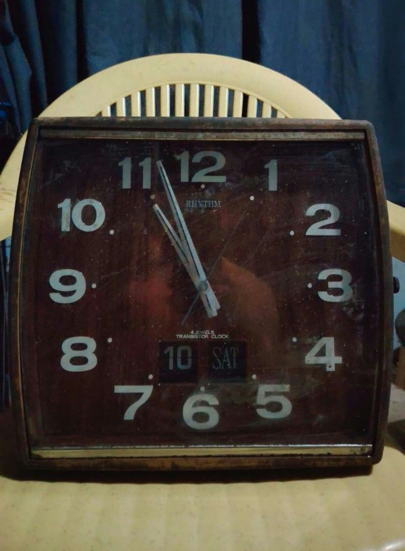 Vintage Rhythm 4 Jewels Transistor Wall Clock (Category: Clocks) located in Caloocan City. Submitted by chuaniki (Listing ID 1467152196, Image 1). Description: - Retro Rhythm square wall clock with dark wood grain background - Features clear, large white numbers for easy reading - Handy date and day of the week display at the bottom center - Reliable battery-operated transistor movement - Ideal size for kitchens, offices, or living rooms - Shows 