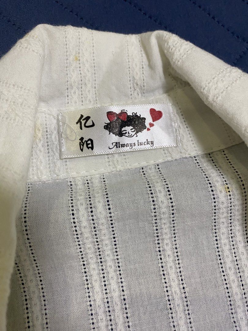 White Blouse Size XS (Category: Blouses) located in Manila. Submitted by escherichiaa (Listing ID 1467137483, Image 2). Description: White long sleeve button-up shirt with vertical stripe texture. Attached dark ribbon tie at the collar. Fitted cut, classic collar design. Lightweight material, easy to style for work or casual days. Tag says Always Lucky with Chinese characters..