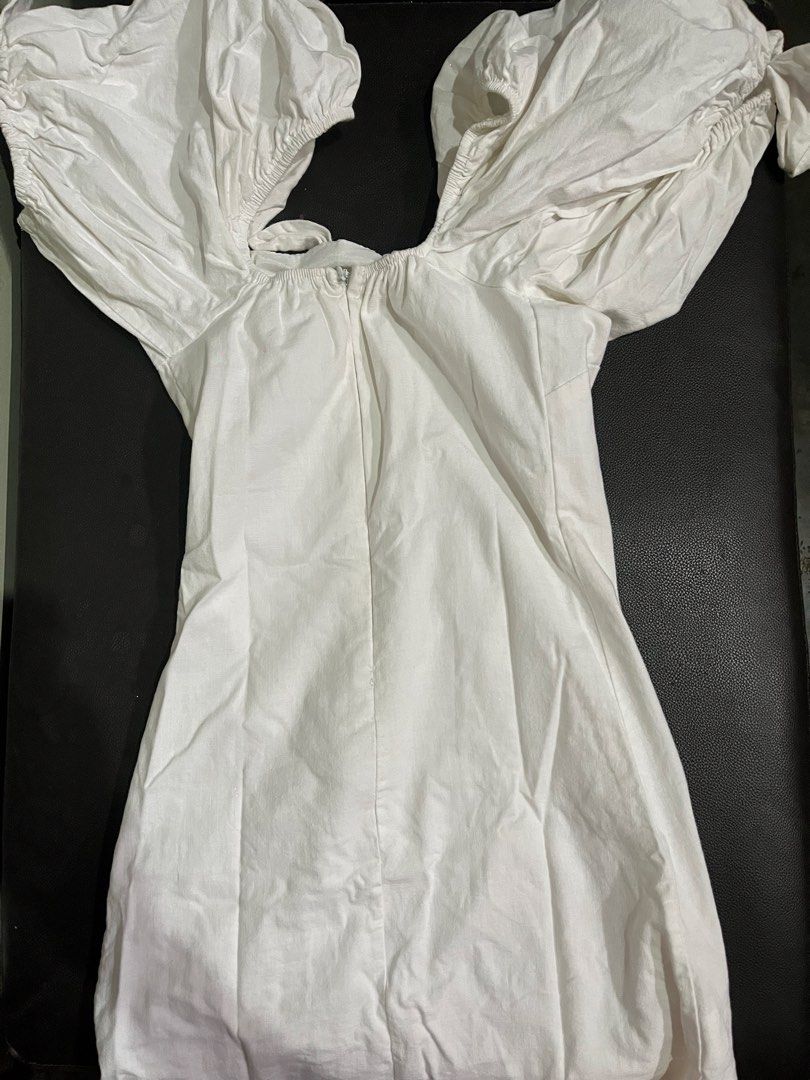 White off-shoulder puff sleeve mini dress (Category: Dresses) located in Manila. Submitted by rhiangastadora (Listing ID 1467036490, Image 2). Description: - Color: White - Style: Off-shoulder mini dress with a fitted bodycon silhouette - Details: Dramatic puff sleeves, sweetheart neckline with front tie, and asymmetrical diagonal hook-and-eye closure - Closure: Convenient back zipper - Ideal for: Resort wear, pool days, and outdoor brunch dates.