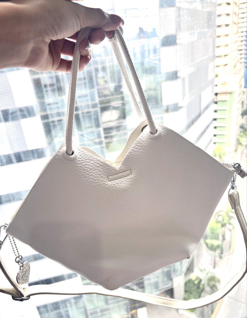 White PU Leather Tote Bag with Shoulder Strap (Category: Tote Bags) located in Makati City. Submitted by bittersweet818ta (Listing ID 1467135827, Image 2). Description: White faux leather handbag with unique petal-shaped top edge. Dual top handles plus an adjustable, detachable long shoulder strap. Includes a cute 'Love' heart charm hanging from the side zip. Main zip closure keeps items secure. Textured finish all over. Clean inside and out. Gre