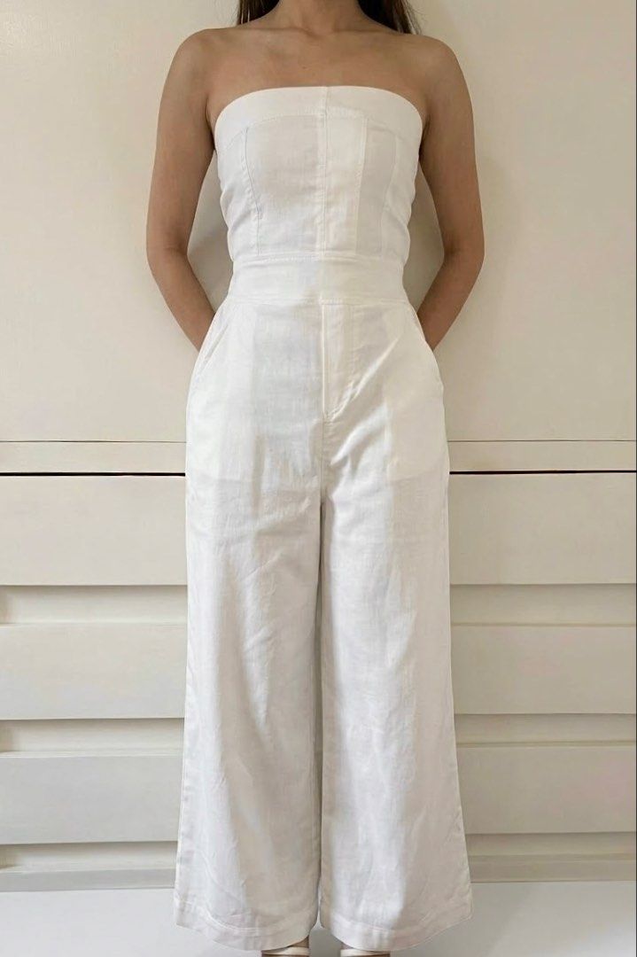 White Strapless Wide-Leg Jumpsuit (Category: Jumpsuits) located in Paranaque City. Submitted by honeykkkk (Listing ID 1467078989, Image 1). Description: • Details: Clean all-white design, structured strapless tube bodice with corseted panel seams, fitted waistband, practical side pockets, and a flattering relaxed wide-leg silhouette. • Condition: Worn a few times, with minimal flaws but in good condition. • Size: Fits XXS to S.