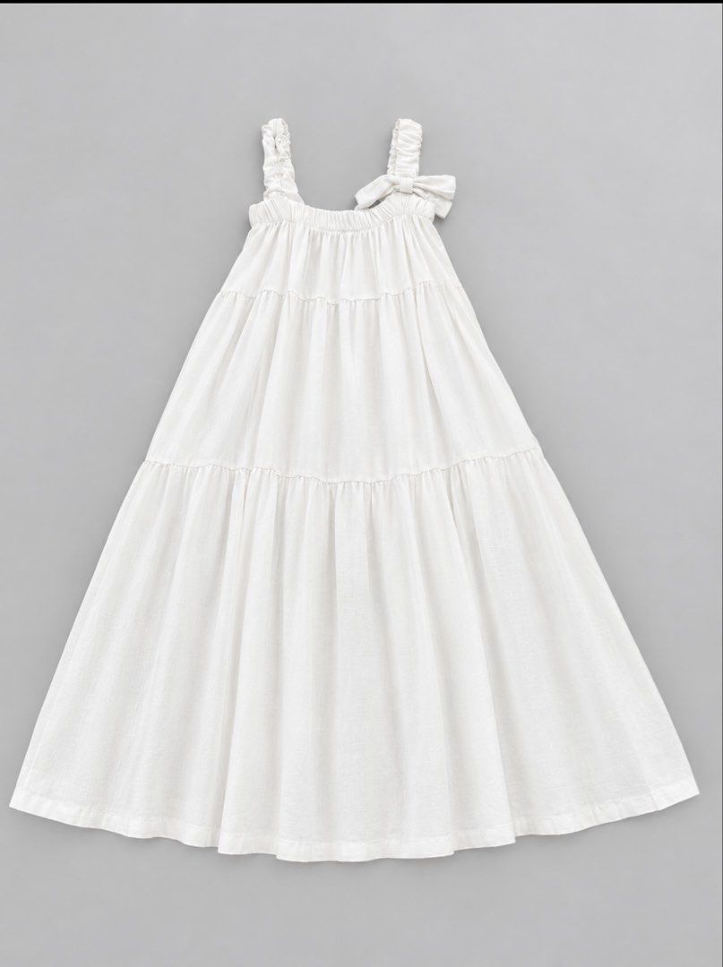 White tiered maxi dress with bow strap (Category: Babies & Kids Fashion) located in Manila. Submitted by bright.atina14 (Listing ID 1467115199, Image 1). Description: - Style: Casual summer maxi dress - Material: Lightweight textured cotton - Fit: Comfortable smocked elastic bodice with easy slip-on design - Design: Long tiered skirt and one-shoulder strap with a decorative bow - Color: White.