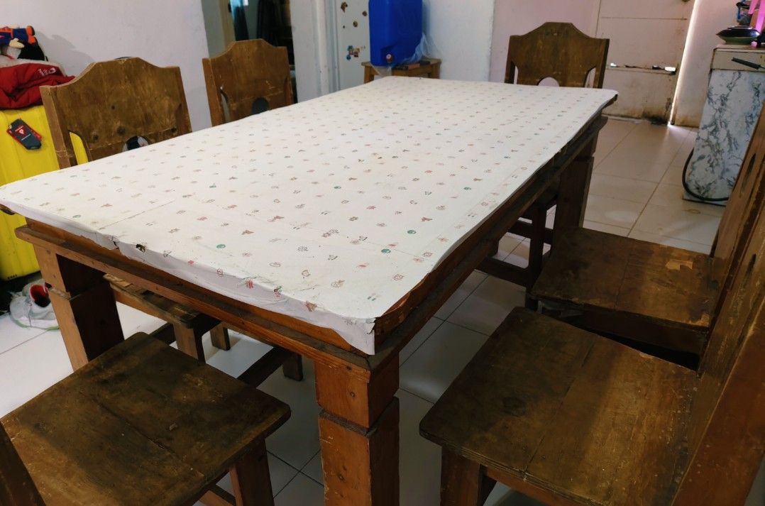 Wooden dining table set with six chairs (Category: Tables & Sets) located in Bulacan. Submitted by babz30261 (Listing ID 1467072508, Image 1). Description: - Solid wooden dining table with rich brown wood grain finish - Includes 6 matching chairs with tall cutout backs and solid wooden seats - Heavy and sturdy construction, great for families and gatherings - Table is currently protected by a patterned top cover - Shows normal signs of previous u
