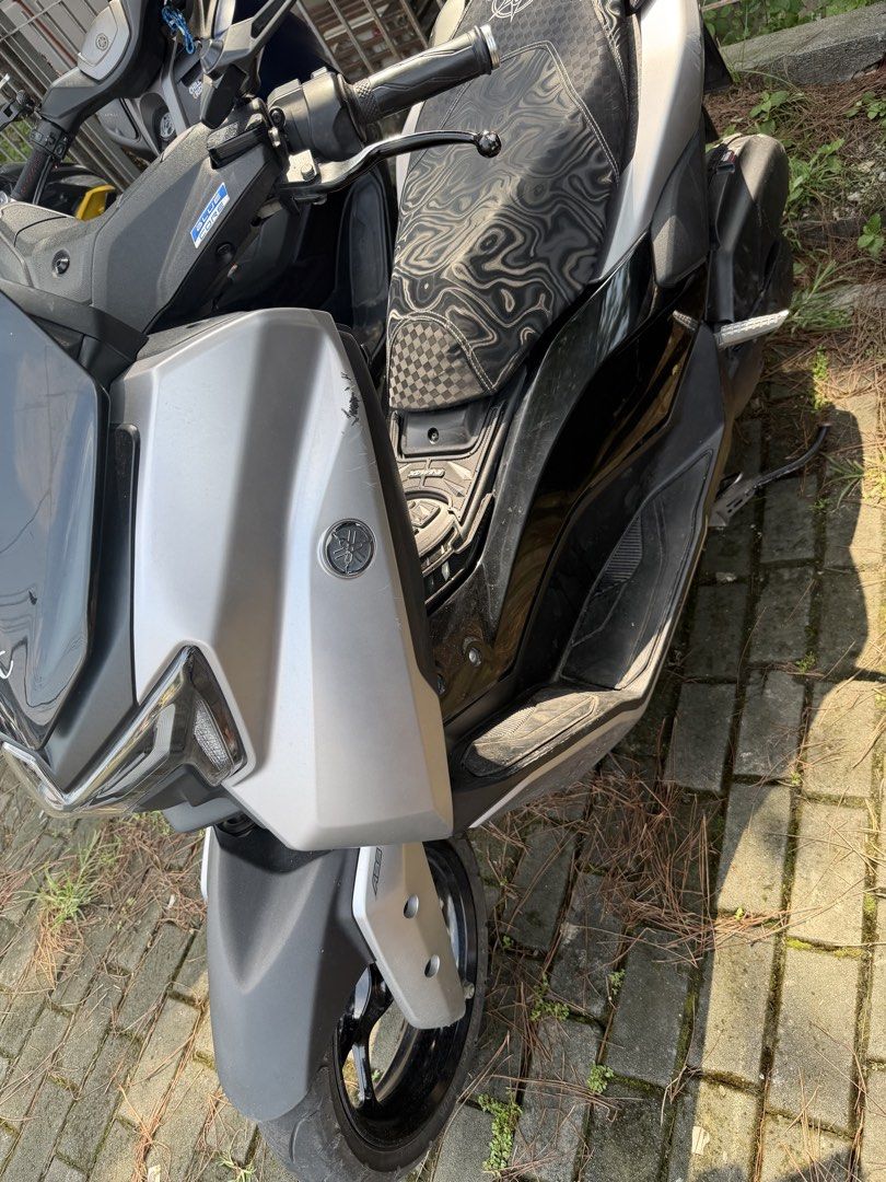 Yamaha NMAX v3 standard (Category: Motorbikes for Sale) located in Manila. Submitted by ballenwilm84291 (Listing ID 1467160018, Image 3). Description: Yamaha NMAX scooter finished in silver and black. Custom patterned seat with a compass-style emblem on top. JVT exhaust pipe installed with a blue tip. Windshield features playing card stickers and a Relax graphic. Dual rearview mirrors attached. Footboards and side panels show normal wear from dai
