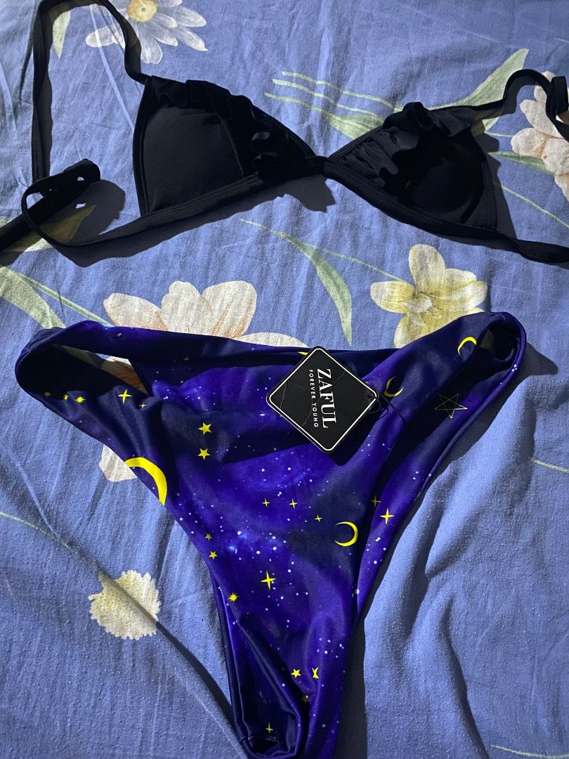 Zaful Galaxy Print Bikini Swimsuit (Category: Bikinis & Swimsuits) located in Makati City. Submitted by dolcevita26 (Listing ID 1467030101, Image 1). Description: - Brand: Zaful - Style: Two-piece swimsuit - Top: Plain black ruffled triangle top with adjustable straps - Bottoms: Galaxy print featuring stars and crescent moons on a deep purple background - Condition: Brand new with tag still attached on the bottom.