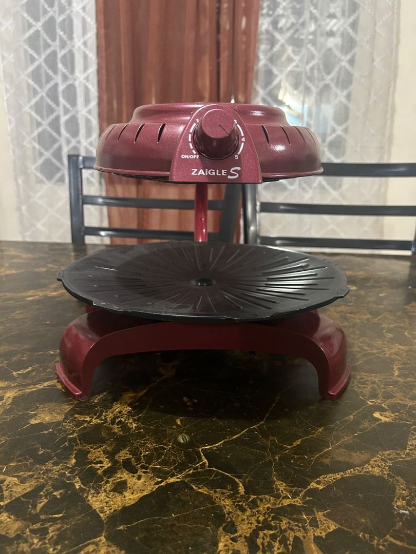 Zaigle S electric smokeless griller (Category: BBQ, Grills & Hotpots) located in Taguig. Submitted by lhadychinitah (Listing ID 1467144644, Image 3). Description: This appliance uses infrared technology to cook food, aiming to reduce fat, odors, and smoke while preventing oil splashes. It features a 3D heating method designed to cook food evenly without needing to flip it frequently. The design includes a rotating cooking plate and an adjustable 