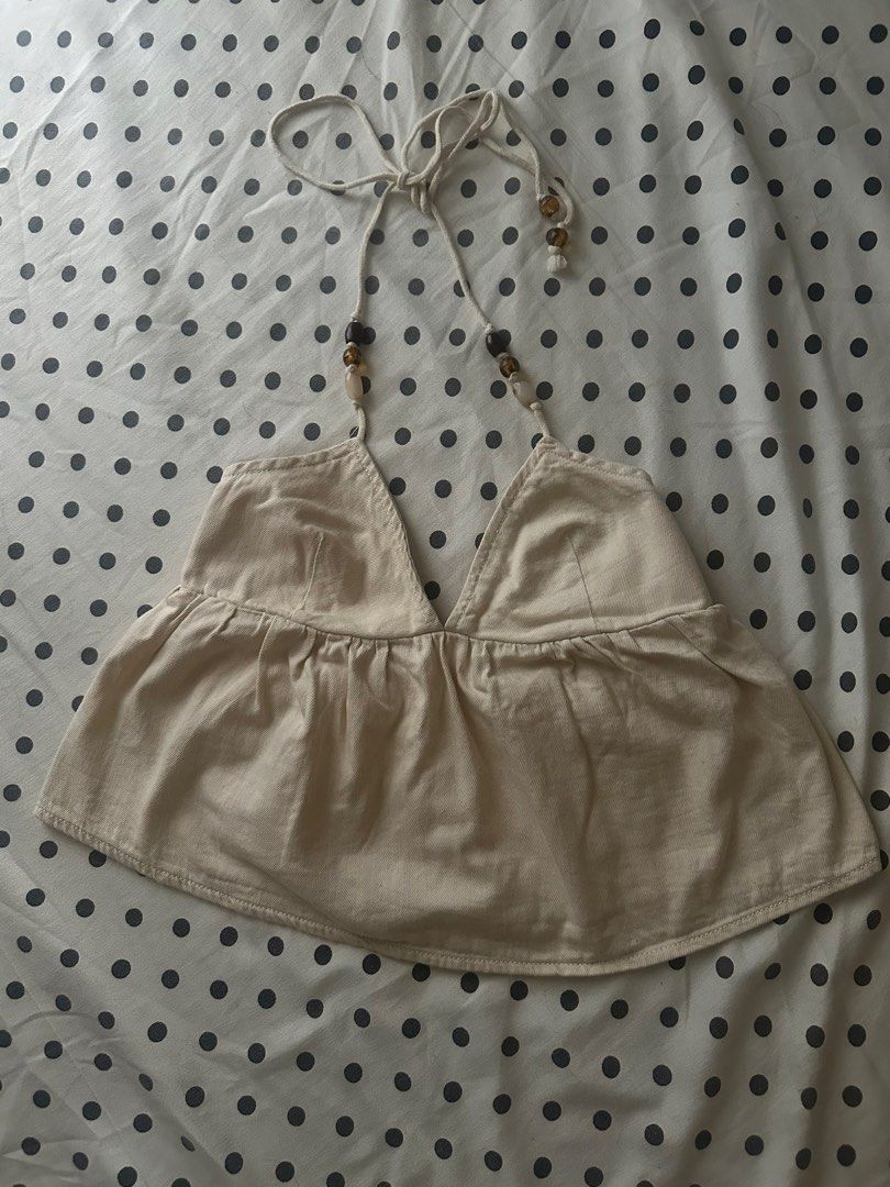 Zara Beaded Halter Top (Category: Sleeveless) located in San Pedro. Submitted by sweetcosmics (Listing ID 1467074417, Image 1). Description: - Brand: Zara - Style: Halter top with plunging V-neckline and backless design - Color: Ecru/Beige - Material: 100% cotton - Details: Adjustable tie straps with brown wooden beads - Fit: Flowy & Slightly cropped - Ideal for: Summer weather, beach trips, and casual outings RFS: Doesnt fit me, but it’s sooo cu