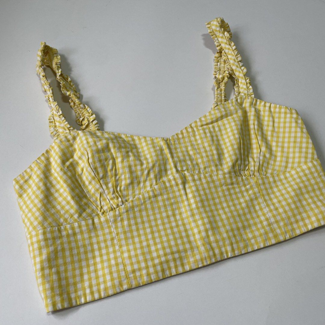 Zara Yellow Gingham Ruffle Strap Crop Top (Category: Sleeveless) located in Pasay City. Submitted by lovedbyzea (Listing ID 1467048849, Image 3). Description: - Color/Pattern: Bright yellow and white gingham - Neckline: Sweetheart neckline with gathered bust cups - Straps: Cute ruffled shoulder straps - Fit: Cropped length with a smocked back panel and convenient side zipper closure - Material: Light and breathable cotton fabric - Styling: Perfec
