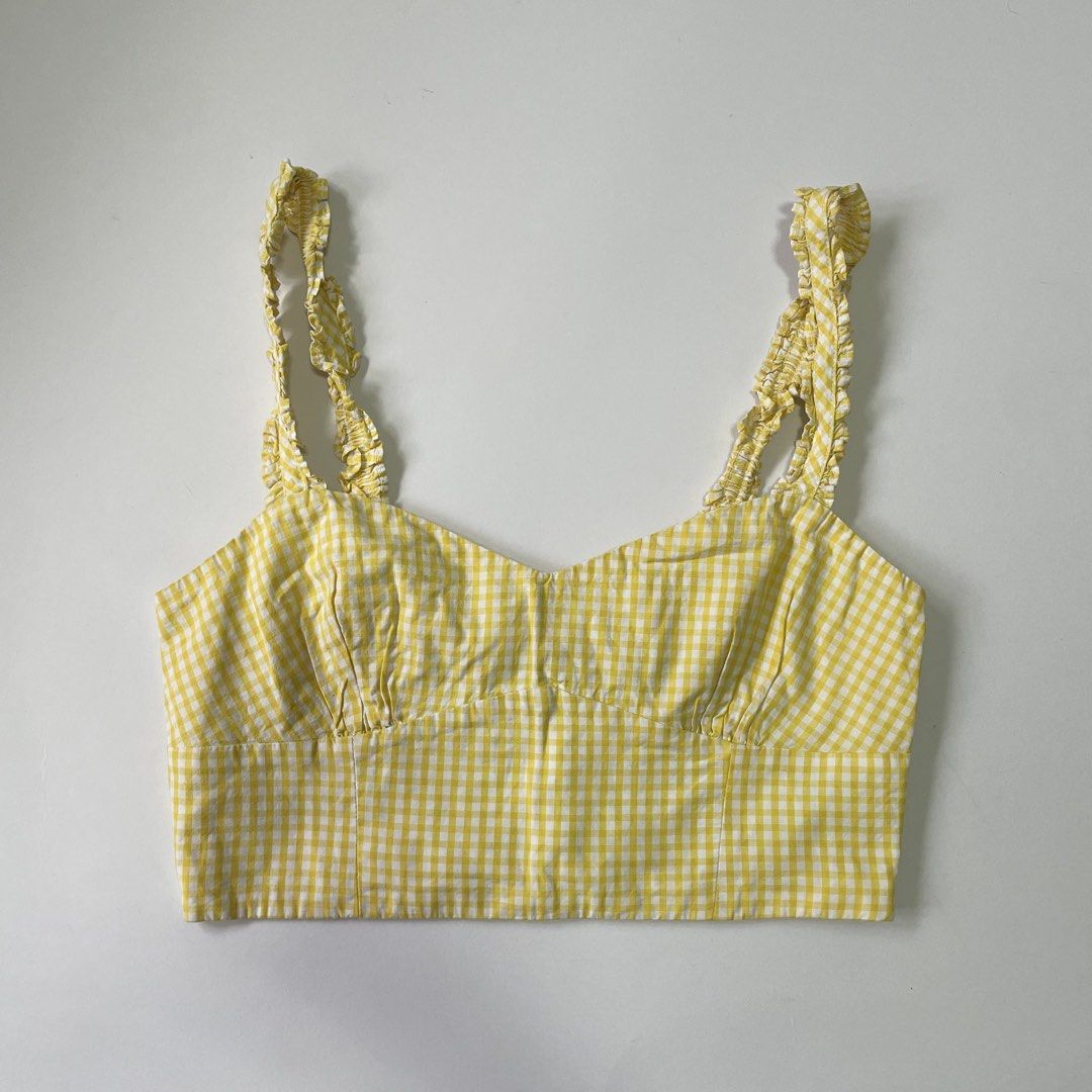 Zara Yellow Gingham Ruffle Strap Crop Top (Category: Sleeveless) located in Pasay City. Submitted by lovedbyzea (Listing ID 1467048849, Image 1). Description: - Color/Pattern: Bright yellow and white gingham - Neckline: Sweetheart neckline with gathered bust cups - Straps: Cute ruffled shoulder straps - Fit: Cropped length with a smocked back panel and convenient side zipper closure - Material: Light and breathable cotton fabric - Styling: Perfec