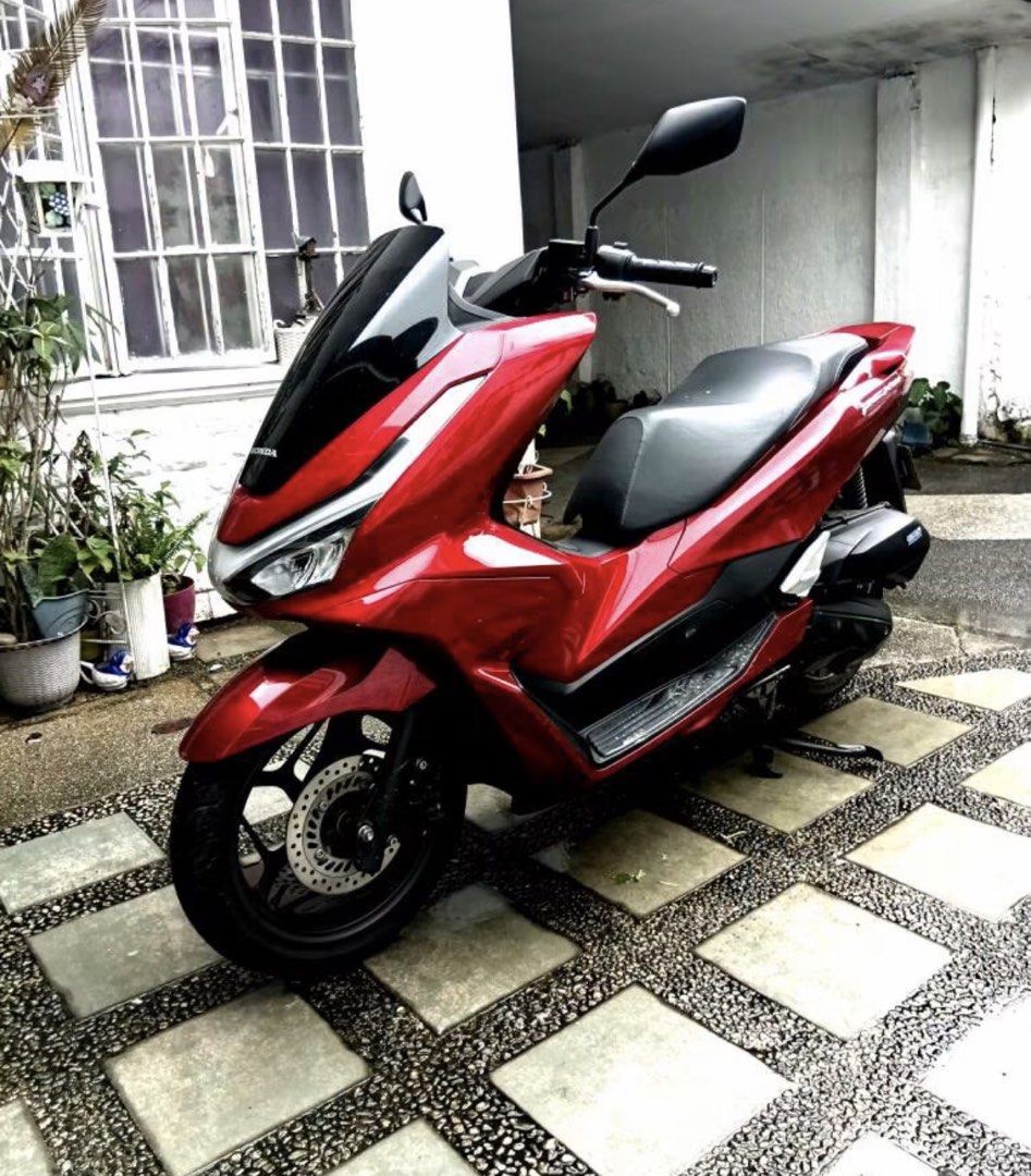 2025 Honda PCX 160 (Category: Motorbikes for Sale) located in Antipolo. Submitted by goldenmoon_33cc19 (Listing ID 1467177500, Image 3). Description: Red Honda PCX 160 scooter, black windshield and mirrors. Clean body panels, dark alloy wheels. Dual headlights with LED strips. Comfortable black seat, standard exhaust pipe. Street-ready commuter bike parked outdoors..