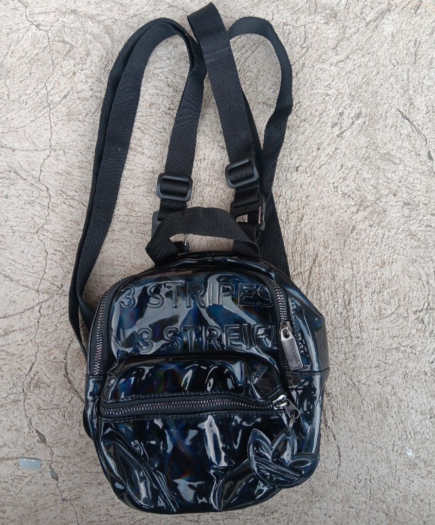 Adidas 3 Stripes Iridescent Mini Backpack Black (Category: Backpacks) located in Cagayan de Oro. Submitted by kokirts17 (Listing ID 1467209710, Image 1). Description: - Color/Finish: Black iridescent with embossed 3 Stripes lettering - Hardware: Matching trefoil zipper puller - Straps: Adjustable shoulder straps with buckles - Compartments: Main zipped compartment, front zipped pocket, and interior open slip pocket - Details: Features Adidas bran
