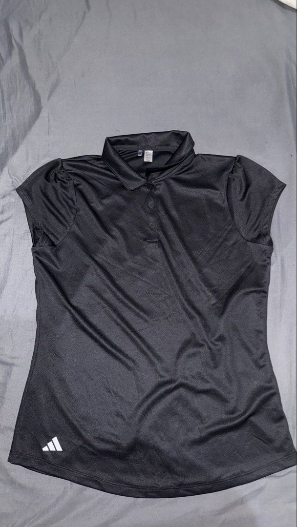 Adidas Black Polo Shirt (Category: Activewear) located in Andop. Submitted by nobleangel (Listing ID 1467310834, Image 1). Description: - Brand: Adidas - Color: Classic Black with white logo near the bottom hem - Size: XL (UK/US 14-15Y) - Material: Lightweight fabric - Design: Collar with button placket - Condition/Origin: Made in Vietnam - Best for: Sports, active use, or everyday casual wear.