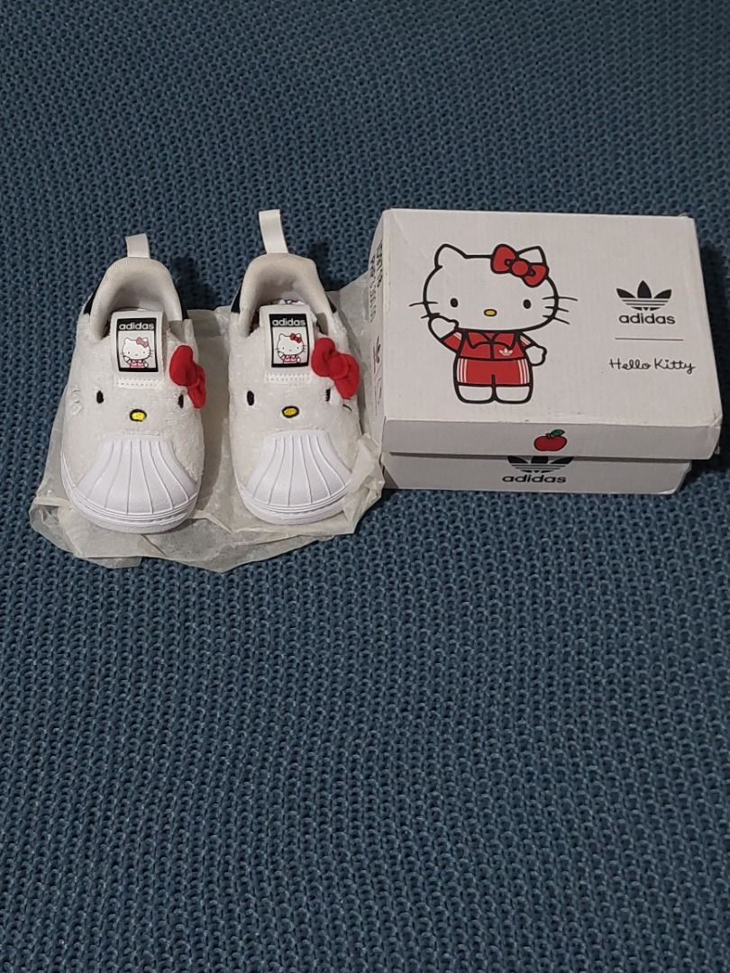Adidas x Hello Kitty Superstar 360 Shoes (Category: Sneakers) located in Las Pinas. Submitted by martinedee (Listing ID 1467217035, Image 2). Description: - Item: Adidas x Kitty Superstar 360 Kids Shoes - Color: White with red bow detail - Size: US 4K / UK 3K / EUR 19 / JP 110 - Features: Soft fuzzy upper, classic shell toe, slip-on design with back pull tab - Condition: Excellent, includes original box - Perfect for daily wear or gifting!.