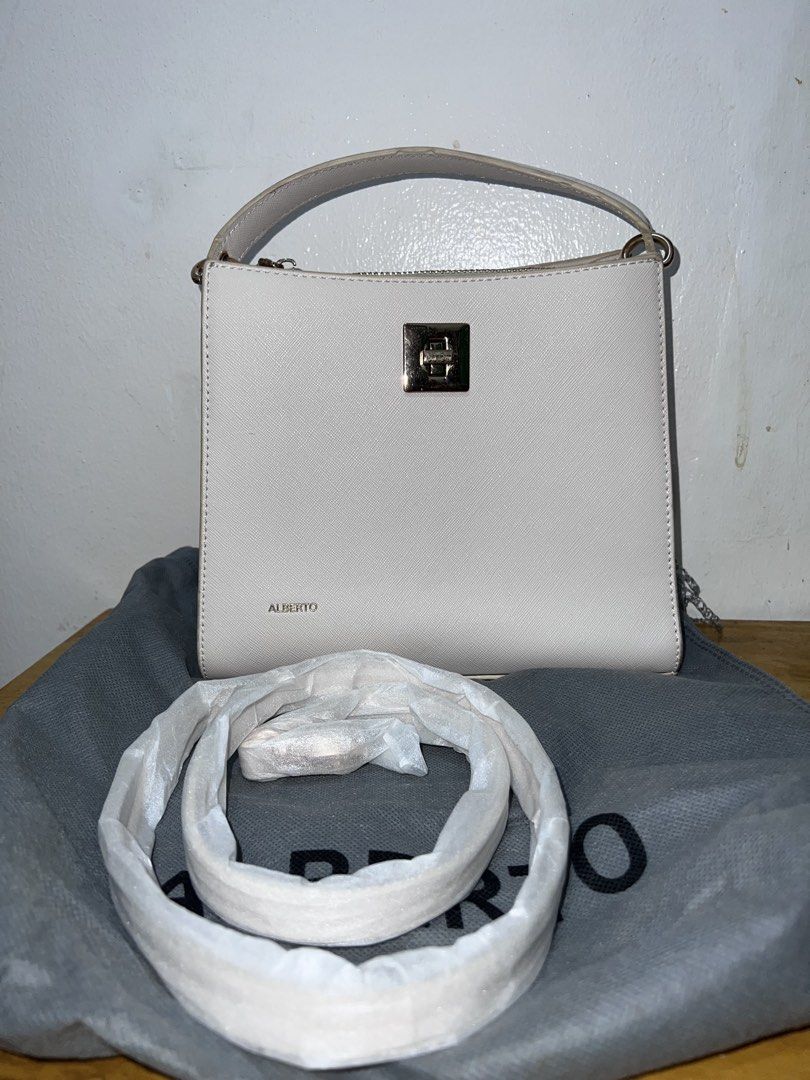 ALBERTO White Structured Handbag with Strap (Category: Luxury Bags & Wallets) located in Manila. Submitted by goldenwater_a772ad (Listing ID 1467271167, Image 1). Description: - Brand: ALBERTO - Color: Classic White - Hardware: Elegant gold-tone closure - Interior: Double main compartments with a secure zipped center pocket - Included: Matching adjustable shoulder strap (still wrapped in protective packaging) and original grey dust bag - Conditio