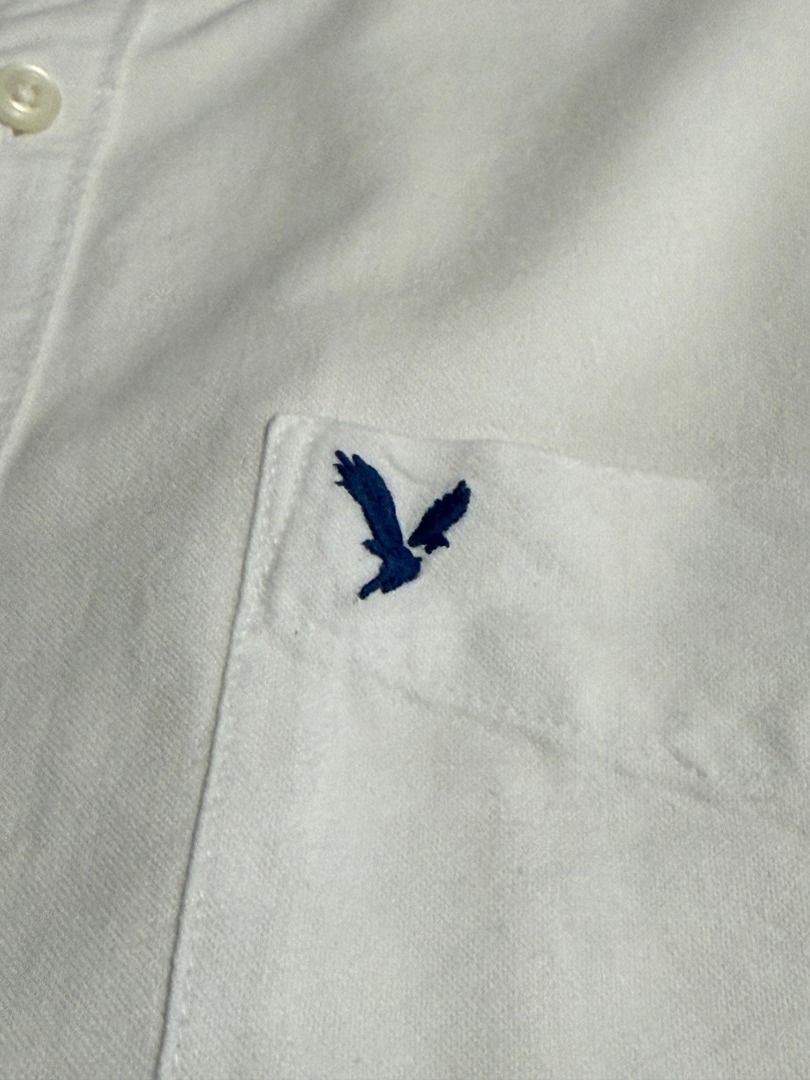 American Eagle Classic Fit White Button-Down Shirt Size L (Category: Tshirts & Polo Shirts ) located in Las Pinas. Submitted by luisanthonydelacruz (Listing ID 1467311057, Image 2). Description: American Eagle white button-down shirt in size Large. Features a classic fit, button-down collar, single chest pocket with embroidered eagle logo, and long sleeves. A versatile, clean wardrobe staple for any occasion..