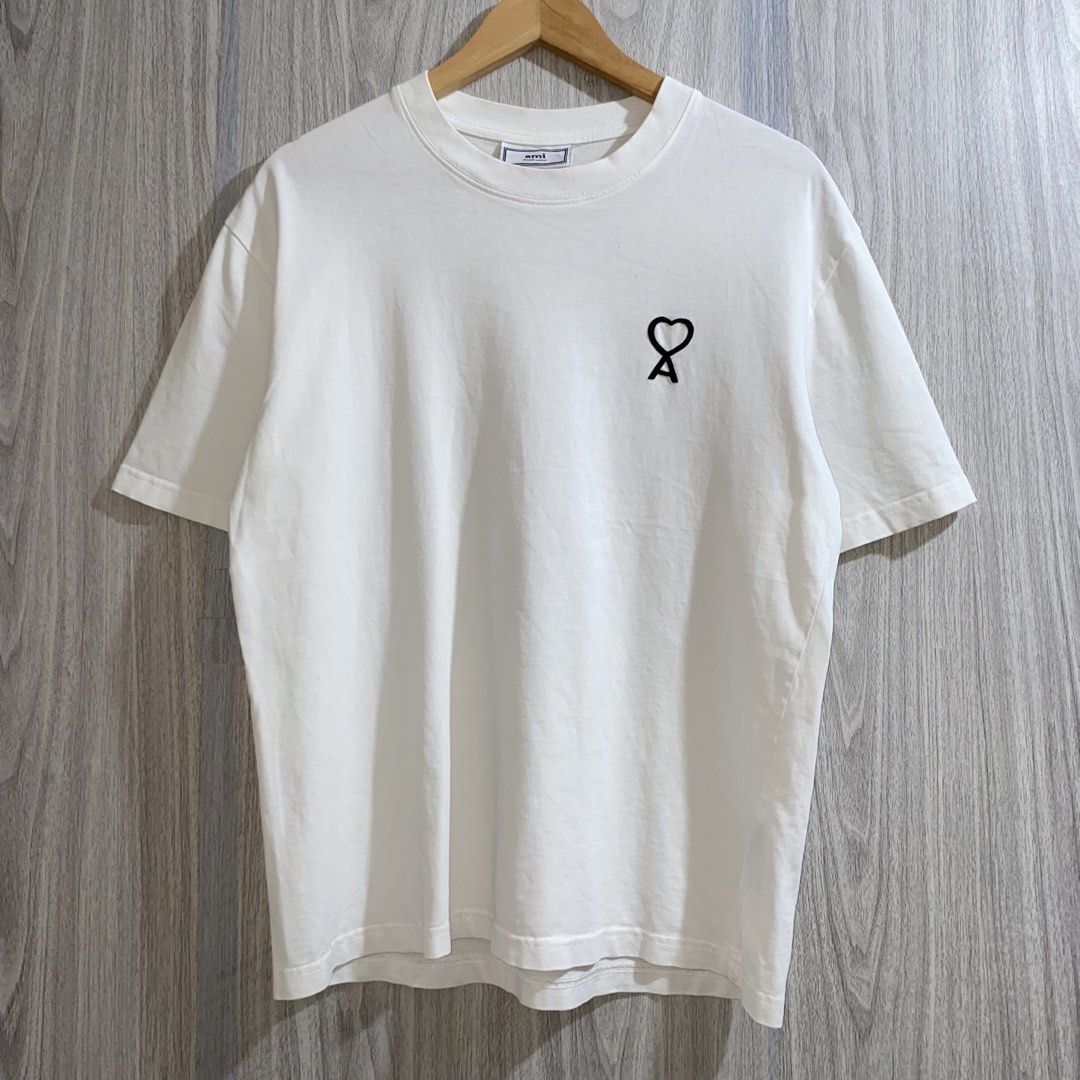 Ami Paris White Heart T-Shirt (Category: Shirts) located in Manila. Submitted by _thriftanddrip (Listing ID 1467276921, Image 1). Description: 22 x 27 Like new ₱700 White t-shirt from Ami Paris. Short sleeves with a ribbed crewneck collar. Features the signature black Ami de Coeur embroidered logo on the chest. Soft cotton fabric, clean styling. Regular fit, easy to match with daily outfits..