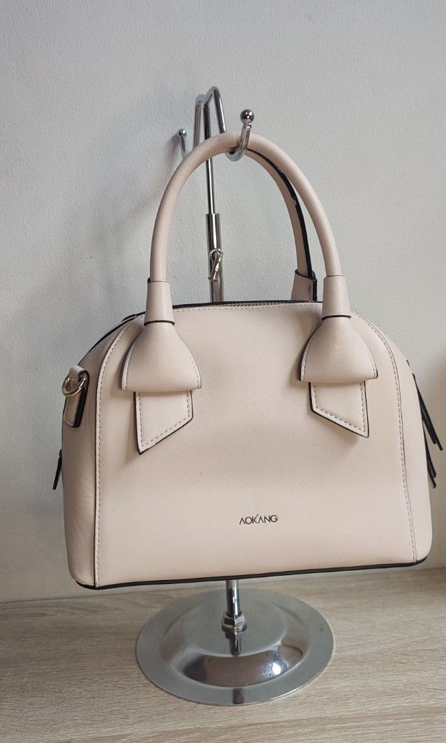 Aokang Bow Detail Dome Handbag (Category: Purses & Pouches) located in Pasig City. Submitted by xcess_baggage (Listing ID 1462054553, Image 1). Description: - Cute Aokang handbag - Light beige color - Adorable bow detail on the front - Classic dome shape - Comfortable top handles - Secure zipper closure - Ideal for everyday use.