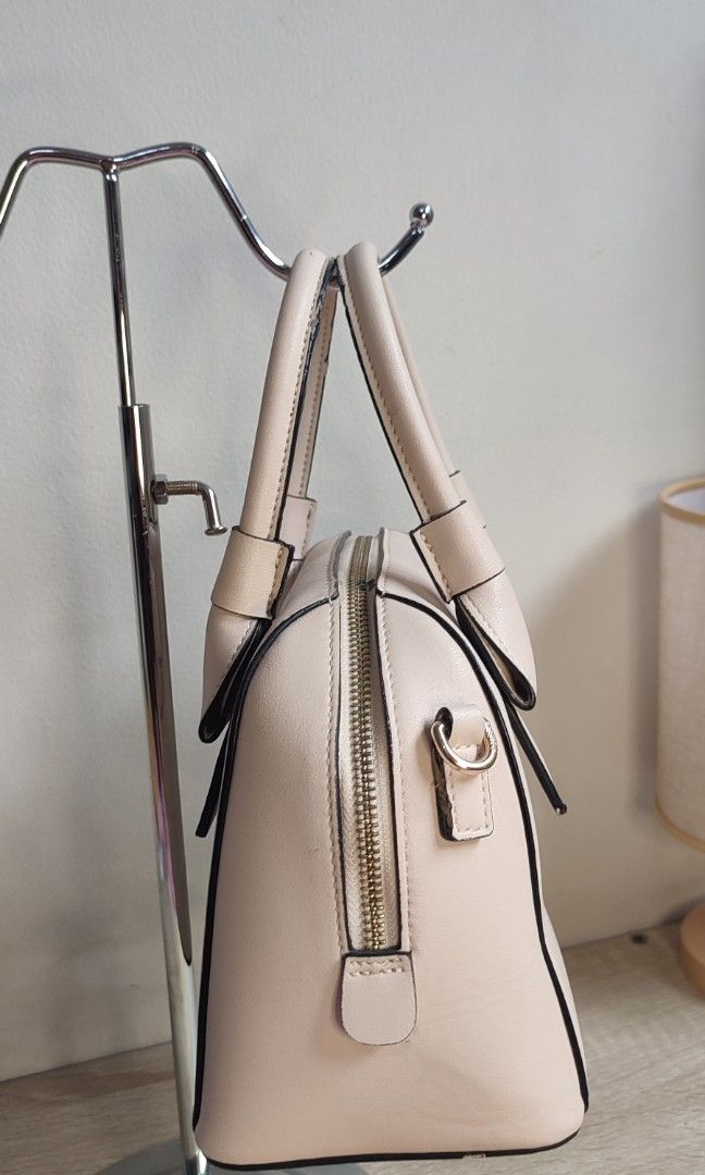 Aokang Bow Detail Dome Handbag (Category: Purses & Pouches) located in Pasig City. Submitted by xcess_baggage (Listing ID 1462054553, Image 3). Description: - Cute Aokang handbag - Light beige color - Adorable bow detail on the front - Classic dome shape - Comfortable top handles - Secure zipper closure - Ideal for everyday use.