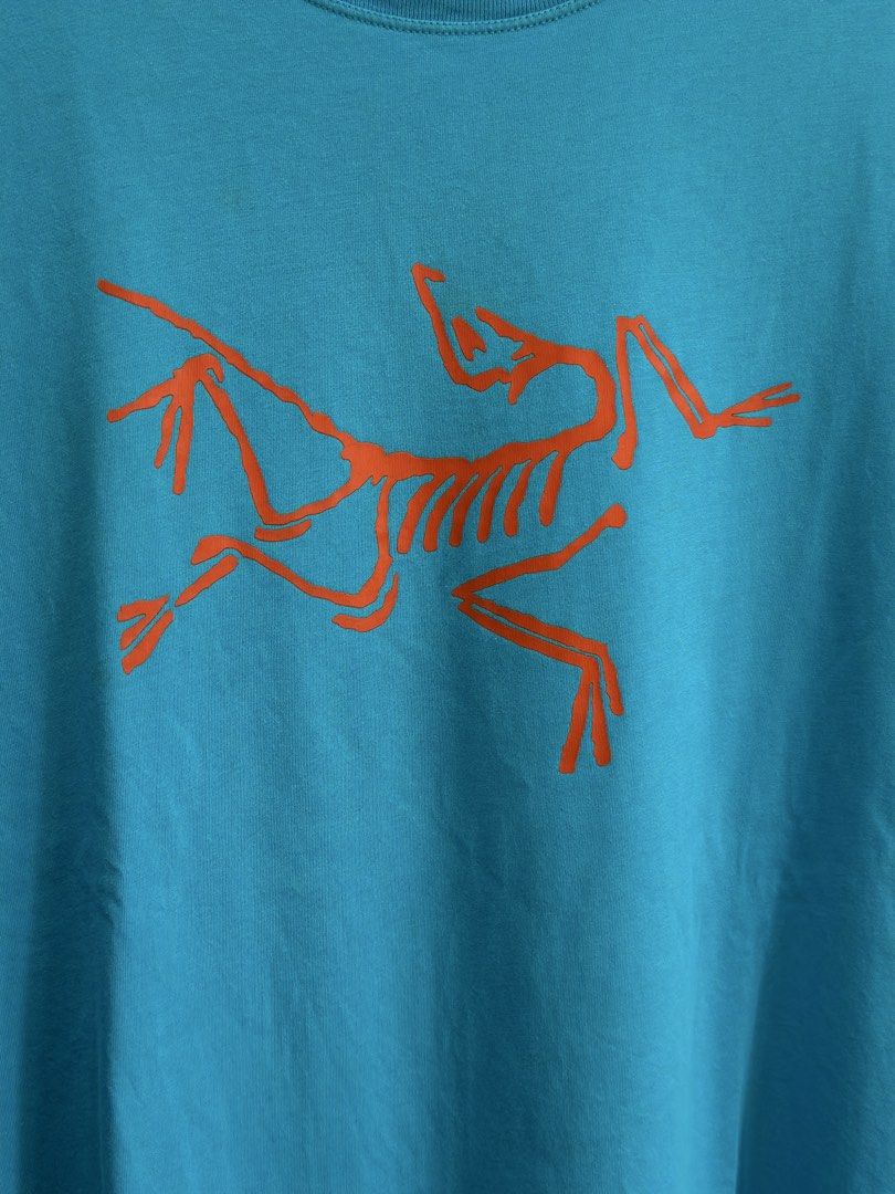Arc'teryx Blue T-Shirt Size XL (Category: Tshirts & Polo Shirts ) located in Daet. Submitted by thrifthings2018 (Listing ID 1467244321, Image 2). Description: Bright blue Arc'teryx t-shirt with large orange bird logo on the front. Size XL for men. Made from 100% cotton in Vietnam. Tag specifies do not use fabric softener. Crew neck style, clean solid blue back..