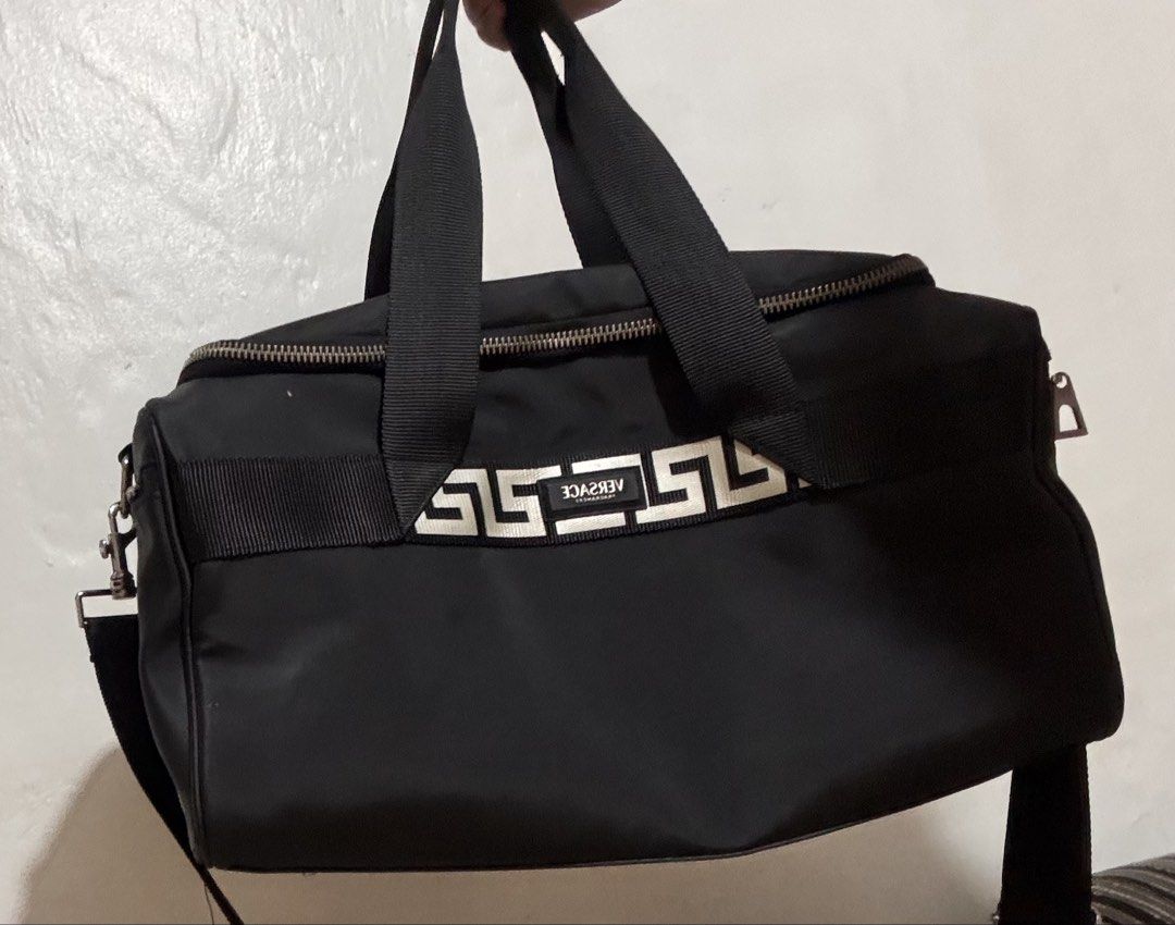 Authentic Versace Black Travel Duffle Bag (Category: Luxury Bags & Wallets) located in Manila. Submitted by cheesetinefinds (Listing ID 1467358074, Image 2). Description: - Authentic Versace travel duffel bag in classic black - Eye-catching white geometric Greek key ribbon detail on the front - Spacious interior ideal for gym sessions, daily use, or weekend trips - Secure dual-zip top opening - Equipped with strong black carrying handles and an a