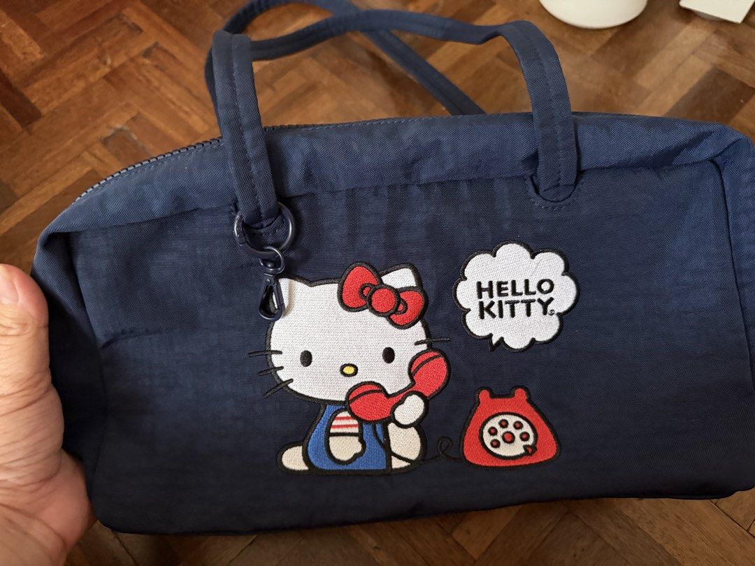 Baggu x Hello Kitty (Category: Tote Bags) located in Pasay City. Submitted by ellen10131995 (Listing ID 1467234619, Image 2). Description: - Color: Navy blue - Design: Embroidered Kitty with red rotary phone and speech bubble patch - Straps: Dual shoulder straps with sturdy dark hardware - Interior: Features a black strap with debossed lettering and a metal ring attachment - Condition: almost new and authentic - Perfect for daily use, school, or 