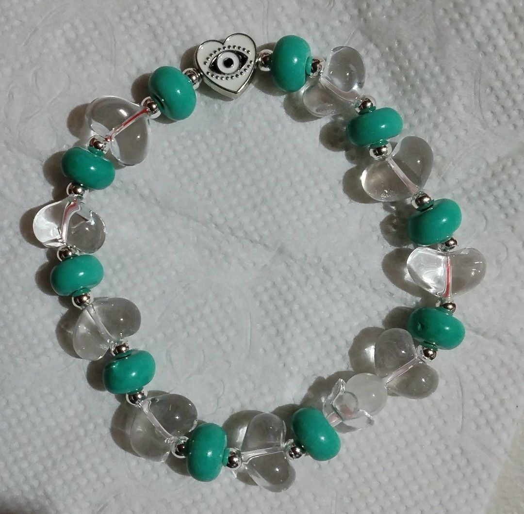 Beaded bracelet with turquoise beads and evil eye charm (Category: Bracelets) located in Makati City. Submitted by clover_2024 (Listing ID 1467353589, Image 1). Description: - Handmade beaded bracelet - Turquoise round beads & clear heart-shaped glass beads - Silver-tone metal spacer beads - Central white heart charm with black evil eye symbol - Stretchy elastic cord fits most wrists - Cute everyday accessory for casual outfits.