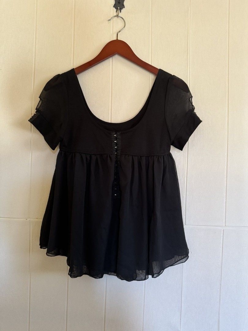 Black blouse with front hook closure and sheer chiffon hem (Category: Blouses) located in Calamba. Submitted by iam.hides (Listing ID 1467206091, Image 1). Description: - Color: Black - Style: Short-sleeve top with scoop neckline and sheer sleeve accents - Closure: Functional metal hook-and-eye closure down the center front - Design: Fitted bodice with a gathered, flowy chiffon skirt layer - Material: Soft cotton blend upper - Length: Approximate