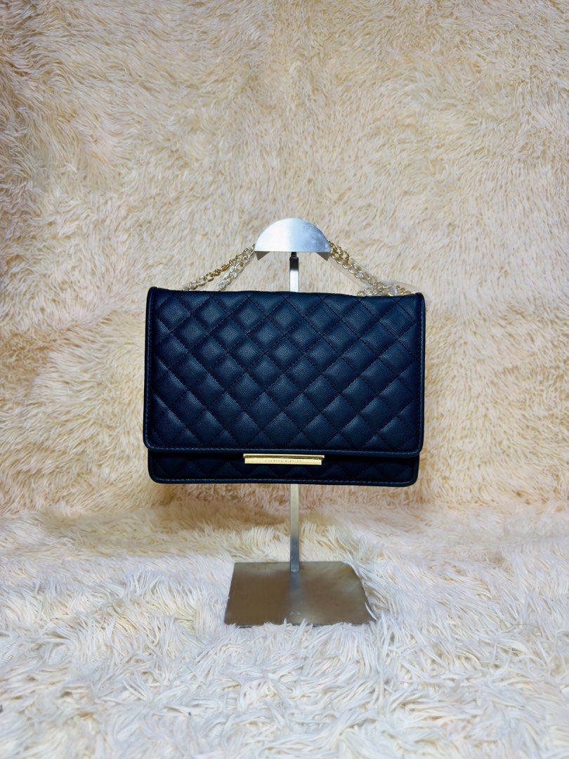 Black Quilted Chain Shoulder Bag (Category: Shoulder Bags) located in Caloocan City. Submitted by hirahira.co (Listing ID 1467285493, Image 1). Description: - Style: Black textured faux leather shoulder bag with diamond quilted pattern - Hardware: Elegant gold-tone chain strap and metallic bar accent - Closure: Front flap closure - Interior: Includes a zipper compartment, slip pockets, and card slots - Condition: Brand new with stuffing paper ins