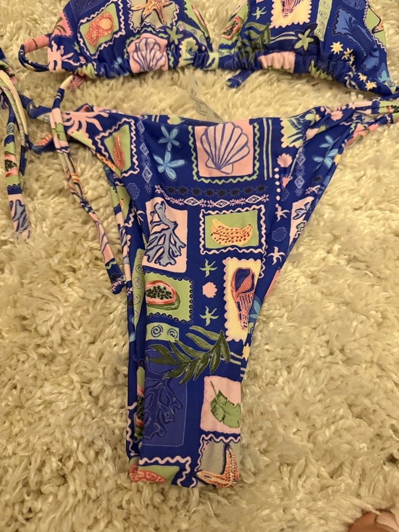 Blue seashell print stamp two-piece bikini set size S (Category: Bikinis & Swimsuits) located in Mandaluyong City. Submitted by riz_040521 (Listing ID 1467208257, Image 3). Description: Worn once - Size: Small - Design: Blue retro beach aesthetic with all-over seashell, starfish, and postage stamp graphics - Top: Triangle style with adjustable string ties - Bottoms: Matching style with adjustable side ties.