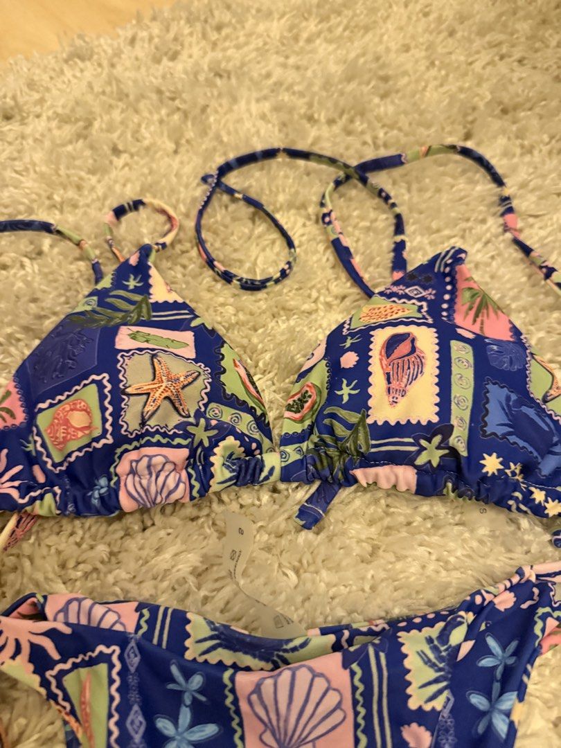 Blue seashell print stamp two-piece bikini set size S (Category: Bikinis & Swimsuits) located in Mandaluyong City. Submitted by riz_040521 (Listing ID 1467208257, Image 2). Description: Worn once - Size: Small - Design: Blue retro beach aesthetic with all-over seashell, starfish, and postage stamp graphics - Top: Triangle style with adjustable string ties - Bottoms: Matching style with adjustable side ties.