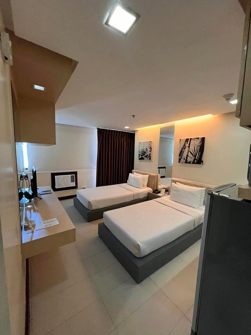 BSA Twin Tower Condominium (Category: Apartments & Condos) located in Muntinlupa City. Submitted by lazoftoys (Listing ID 1467256002, Image 1). Description: - Twin bed studio unit, ready to move in - Private bathroom with glass shower enclosure - Built-in kitchenette with microwave and refrigerator - TV setup and air conditioning installed - Ample overhead storage cabinets and wardrobe space - Sleek, modern, and well-maintained finish.