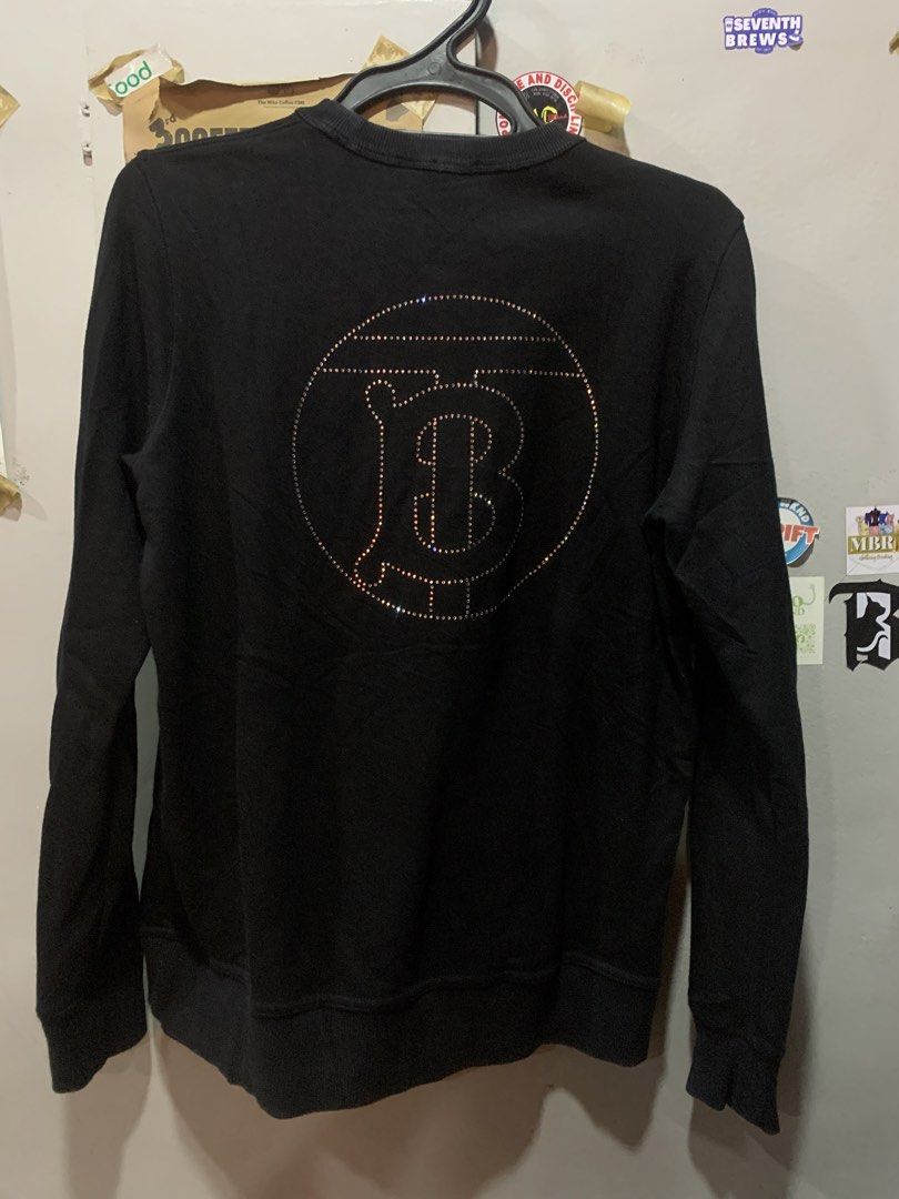 Burberry Black Crystal Logo Sweatshirt (Category: Luxury Apparel) located in Cagayan de Oro. Submitted by agboysalis60090 (Listing ID 1467338796, Image 2). Description: Black crewneck sweatshirt from Burberry London England. Made in Portugal. 100 percent cotton body with elastane blend ribbing. Size small tag attached. Small embroidered lettering on the chest. Large crystal rhinestone monogram logo graphic on the back. Long sleeves with ribbed cu