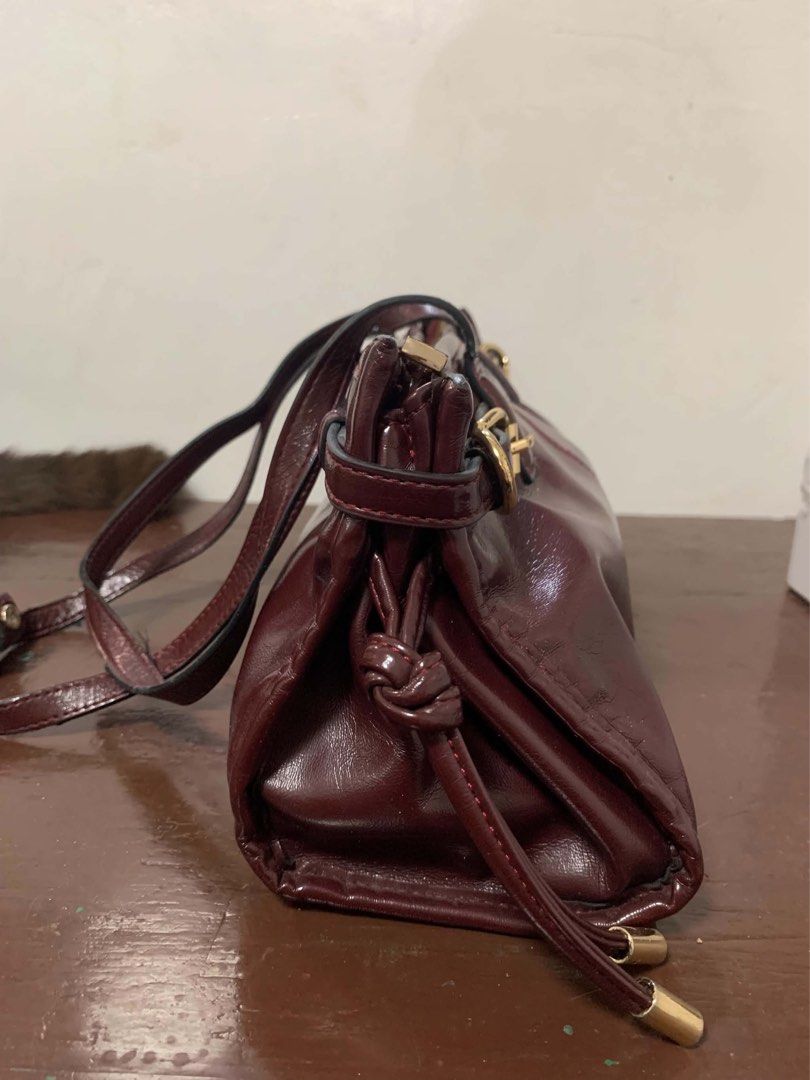 Burgundy Shoulder Bag (Category: Luxury Bags & Wallets) located in Borongan. Submitted by kabes_jane (Listing ID 1467191347, Image 2). Description: - Color: Deep burgundy with a glossy finish - Design: Structured rectangular shape with gold-tone hardware and buckle accents - Handles: Dual top handles for easy carrying - Closure: Secure top zipper closure - Interior: Spacious main compartment for all your daily essentials - Condition: Clean finish