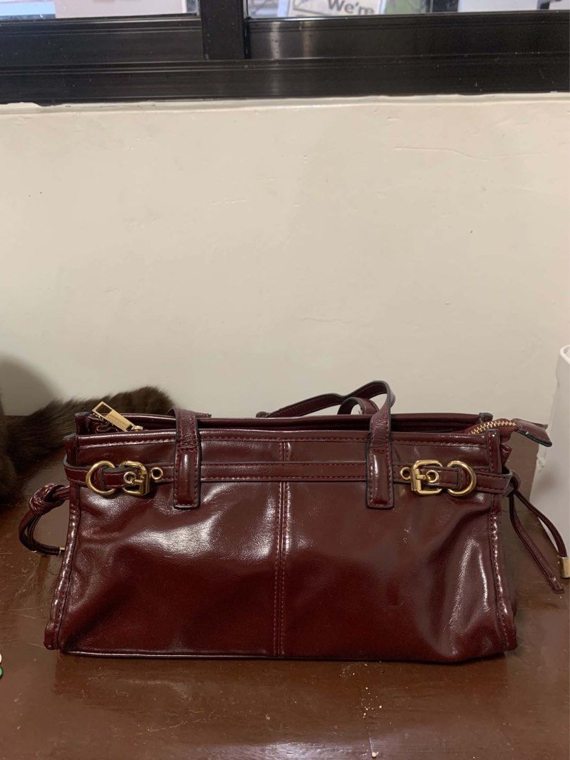 Burgundy Shoulder Bag (Category: Luxury Bags & Wallets) located in Borongan. Submitted by kabes_jane (Listing ID 1467191347, Image 1). Description: - Color: Deep burgundy with a glossy finish - Design: Structured rectangular shape with gold-tone hardware and buckle accents - Handles: Dual top handles for easy carrying - Closure: Secure top zipper closure - Interior: Spacious main compartment for all your daily essentials - Condition: Clean finish