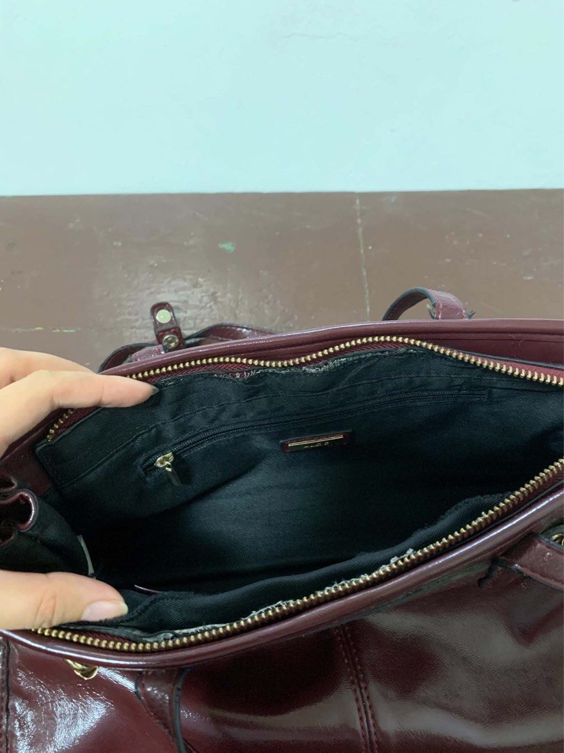 Burgundy Shoulder Bag (Category: Luxury Bags & Wallets) located in Borongan. Submitted by kabes_jane (Listing ID 1467191347, Image 3). Description: - Color: Deep burgundy with a glossy finish - Design: Structured rectangular shape with gold-tone hardware and buckle accents - Handles: Dual top handles for easy carrying - Closure: Secure top zipper closure - Interior: Spacious main compartment for all your daily essentials - Condition: Clean finish