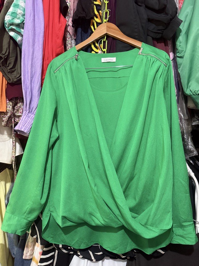 Calvin Klein Green Wrap Blouse (Category: Blouses) located in Antipolo. Submitted by harlowwillow (Listing ID 1467173551, Image 3). Description: 🙅‍♀️NO TO LOW BALLERS No size on tag W L - Color: Bright green - with green inner like - Style: Wrapped front design with zipper hardware on both shoulders - Sleeves: Long sleeves with button cuffs and can be folded - Fabric: Soft drape, comfortable fit - Condition: Good, with tiny dark ink mark on the 