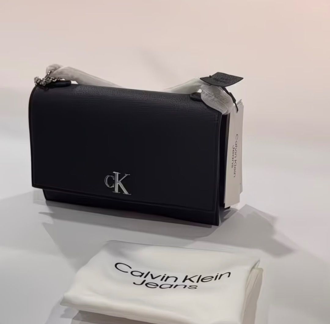Calvin Klein Jeans Black Shoulder Bag (Category: Shoulder Bags) located in Pasay City. Submitted by kgemsluxuryboutique (Listing ID 1467339942, Image 2). Description: - Brand: Calvin Klein Jeans - Style: Crossbody bag - Color: Classic Black - Material/Texture: Structured pebbled finish - Hardware: Silver-tone with prominent front CK logo - Strap: Stylish metal chain links - Condition: Brand new with tags attached, includes original dust bag PLEAS