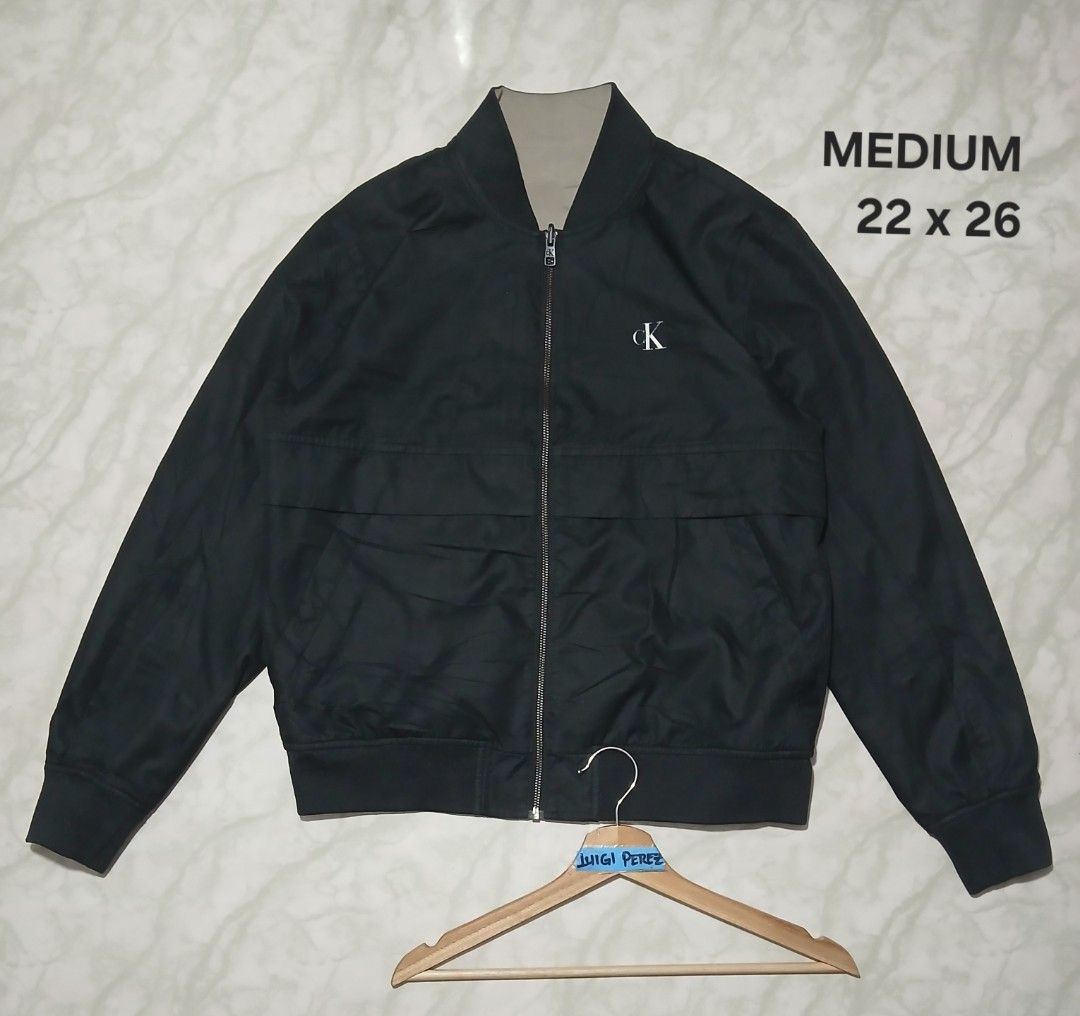Calvin Klein Reversible Bomber Jacket Medium (Category: Coats, Jackets and Outerwear) located in Plaridel. Submitted by igieperez147282 (Listing ID 1467304692, Image 3). Description: - Brand: Calvin Klein - Style: Reversible bomber jacket - Size: Medium (Measures 22" x 26") - Colorway: Beige on one side, Black on the other - Details: Large CK logo printed on the black side, chest zipper pocket - Condition: Great outerwear piece for cooler weather