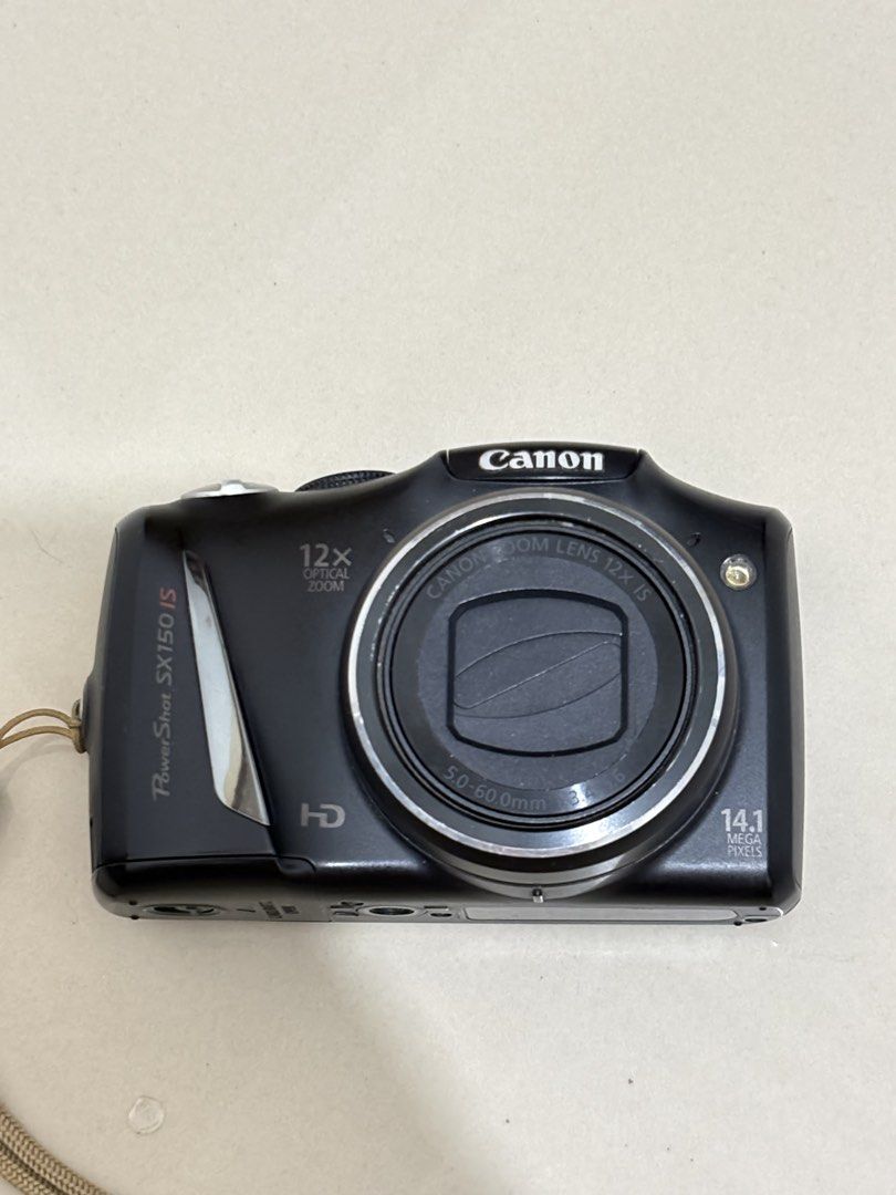 Canon PowerShot SX150 IS Digital Camera (Category: Cameras) located in Manila. Submitted by nicoleannejns (Listing ID 1467356045, Image 1). Description: - Model: Canon PowerShot SX150 IS (Black) - Resolution: 14.1 Megapixels with 12x Optical Zoom - Condition: Tested and works perfectly - Power: Uses standard AA batteries - Inclusions: Eveready battery charger, 2 rechargeable batteries, camera pouch, and attached wrist strap - Perfect for: Everyda
