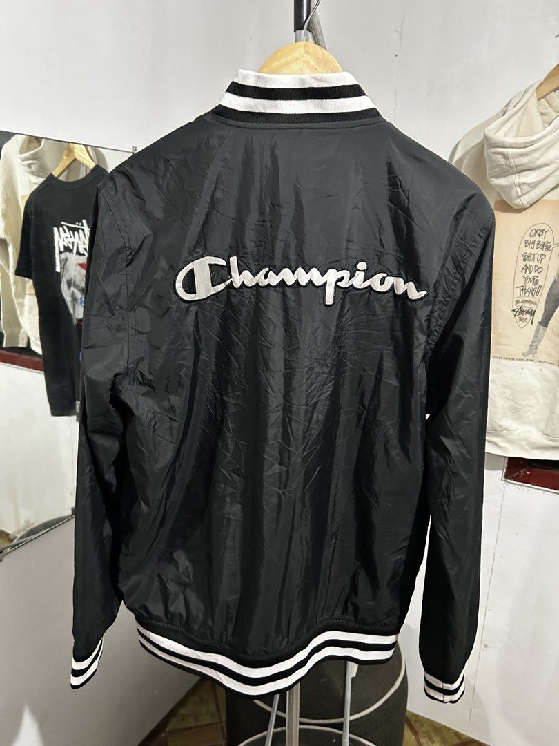 Champion Black Varsity Bomber Jacket Large (Category: Coats, Jackets and Outerwear) located in Manila. Submitted by livedog-d301 (Listing ID 1467311824, Image 2). Description: - Brand: Champion - Style: Varsity jacket with full zip closure - Color: Black with bold white embroidered logos (chest and back) - Size: Large - Details: Striped rib-knit collar, cuffs, and hem, with red mesh interior lining - Origin: Made in Vietnam - Condition: Ready to 
