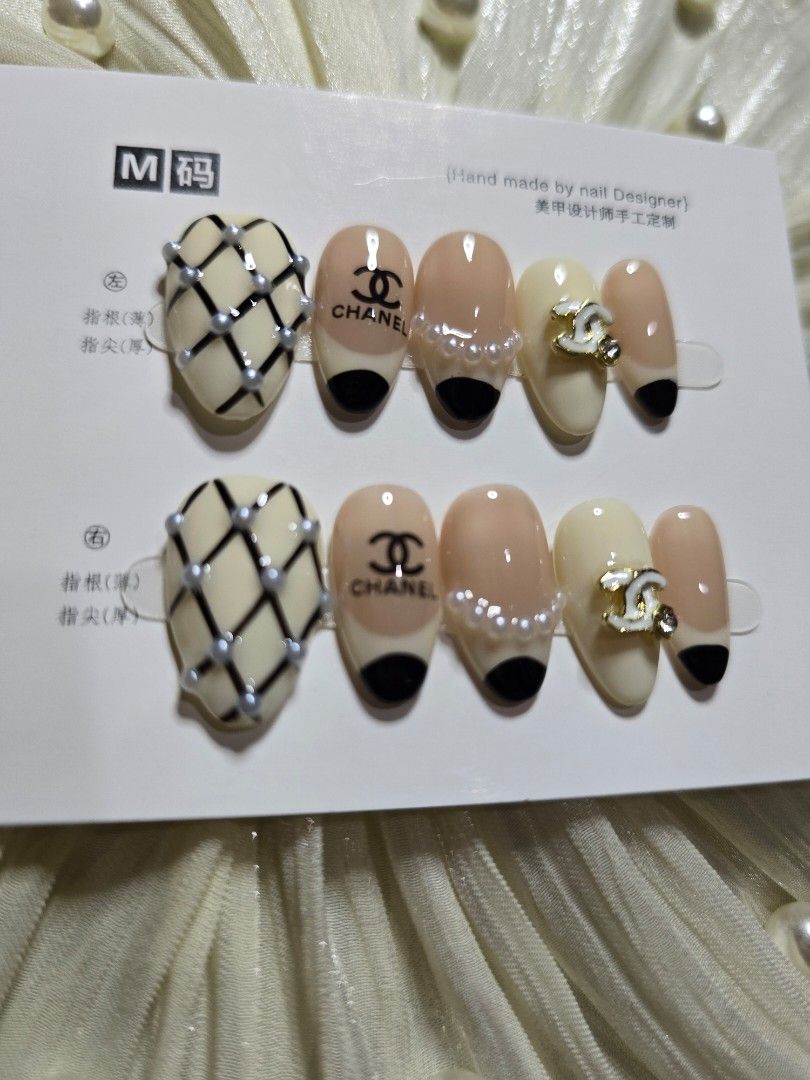 Chanel Inspired Press On Nails Size M Short Almond (Category: Hands & Nails) located in Makati City. Submitted by jangmiscloset (Listing ID 1467313608, Image 2). Description: - Handmade press-on nail set in Size M - Design: Classic beige & black French tips, pearl accents, quilted tweed pattern, and interlocking CC logos - Condition: Brand new, unused, and still on original display card - Includes complete application kit: nail file, wooden cutic