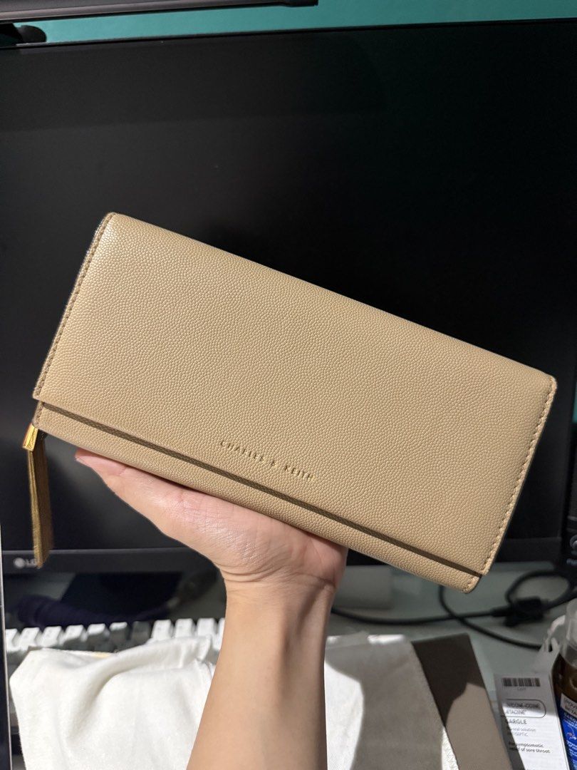Charles & Keith Beige Long Wallet with Tassel (Category: Wallets & Card holders) located in Cavite. Submitted by justcallmejil (Listing ID 1467328249, Image 2). Description: Charles & Keith muriel front flap long wallet ✨ pebbled leather ✨ color sand ✨ 18 card slots ✨ 3 bill compartments (2 inside, 1 at the back) ✨ Huge zipper compartment for coins With box and dustbag (need lang labhan) Used but not abused ₱999 📍 Shipping from Pasig.