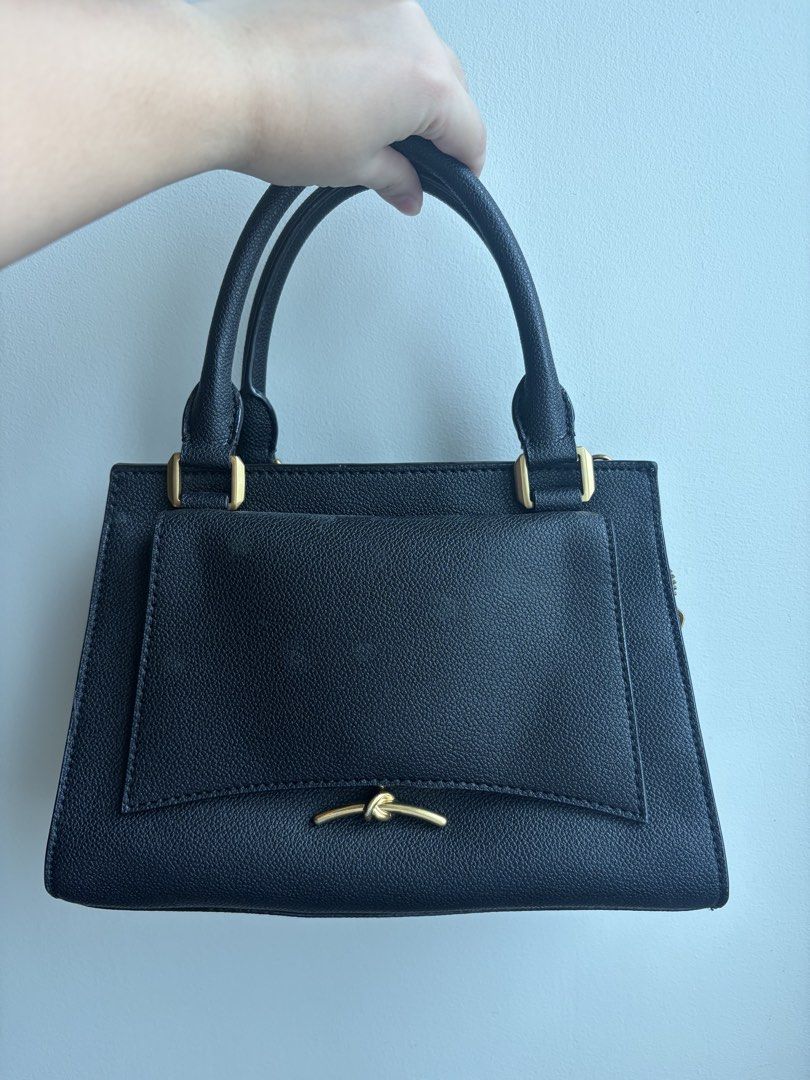 Charles & Keith Black Structured Tote Handbag (Category: Tote Bags) located in Makati City. Submitted by biancabuysells (Listing ID 1467232447, Image 1). Description: - Brand: Charles & Keith - Color: Classic Black with premium gold-tone hardware - Material: Clean pebbled leatherette finish - Design: Elegant front knot detail and branded zipper pull - Handles: Double top handles with stylish rectangular ring attachments - Closure: Secure top zip 
