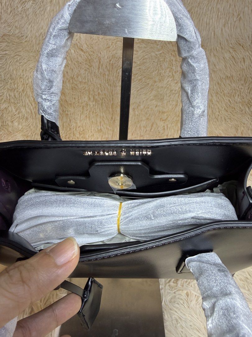 Charles & Keith Black Tote Bag (Category: Tote Bags) located in Caloocan City. Submitted by hirahira.co (Listing ID 1467283265, Image 3). Description: - Brand: Charles & Keith - Color: Classic black with sleek gold-tone side hardware - Design: Structured compact everyday bag with a clean, smooth finish - Handles: Dual top handles (still wrapped in protective paper) - Details: Includes an attached front dangling key charm - Condition: Brand new an