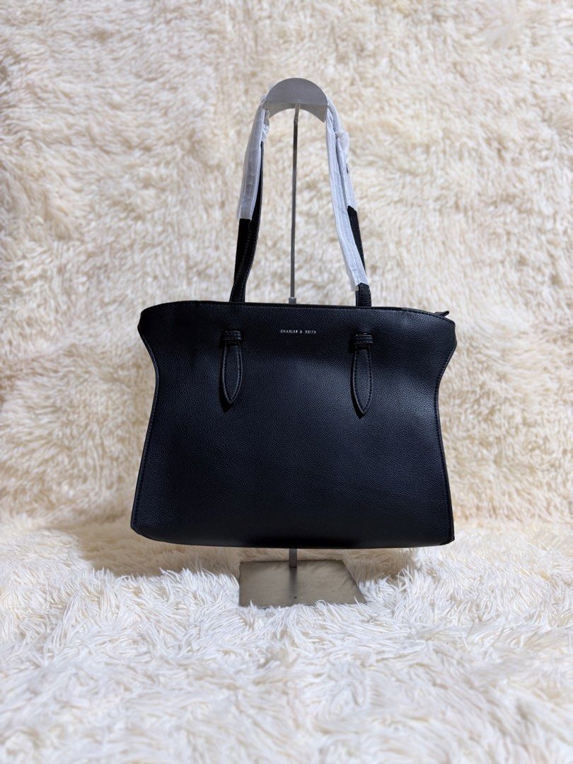 Charles & Keith Black Tote Bag (Category: Tote Bags) located in Caloocan City. Submitted by hirahira.co (Listing ID 1467289708, Image 1). Description: - Brand: Charles & Keith - Color: Classic black with clean pebble texture - Hardware: Silver-tone with front logo lettering - Straps: Twin shoulder straps wrapped in protective foam - Interior: Generous space with an inner zipper pocket - Condition: Brand new, still stuffed with original packing pa