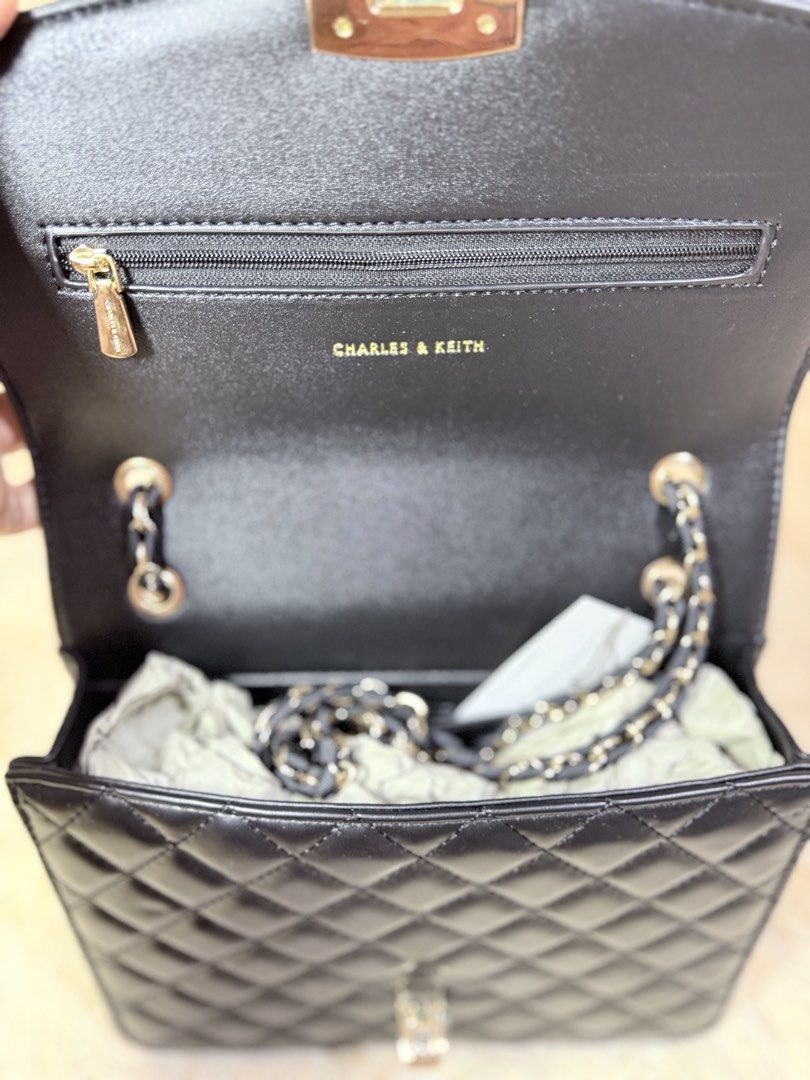 Charles & Keith Quilted Black Handbag with Chain Strap (Category: Luxury Bags & Wallets) located in Caloocan City. Submitted by hirahira.co (Listing ID 1467289351, Image 3). Description: - Brand: Charles & Keith - Style: Black quilted crossbody bag with flap closure - Hardware: Elegant silver and gold twist lock - Straps: Versatile top handle and interwoven chain strap - Interior: Fabric-lined with a zip pocket and gold-foil logo stamp - Conditio